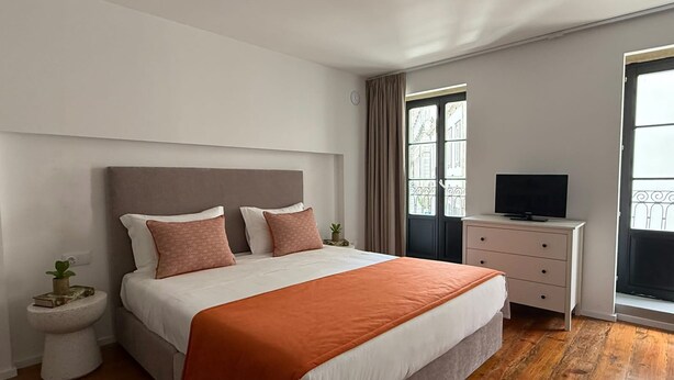 A bedroom with a bed, bedside table, TV, and a window with curtains. - Oporto Riverside Apartments (Porto)