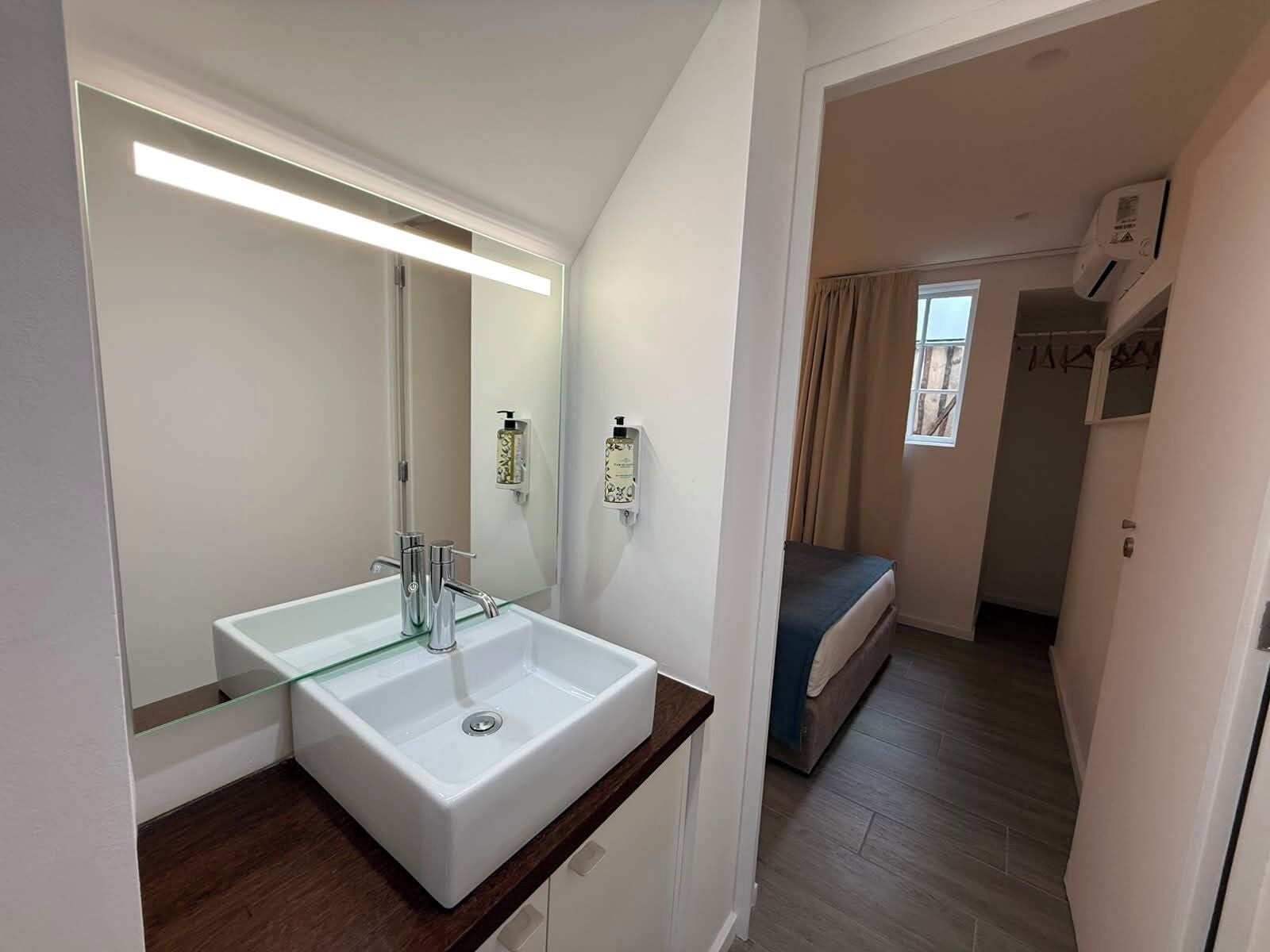 Une salle de bain moderne avec un grand miroir, deux lavabos et une douche.