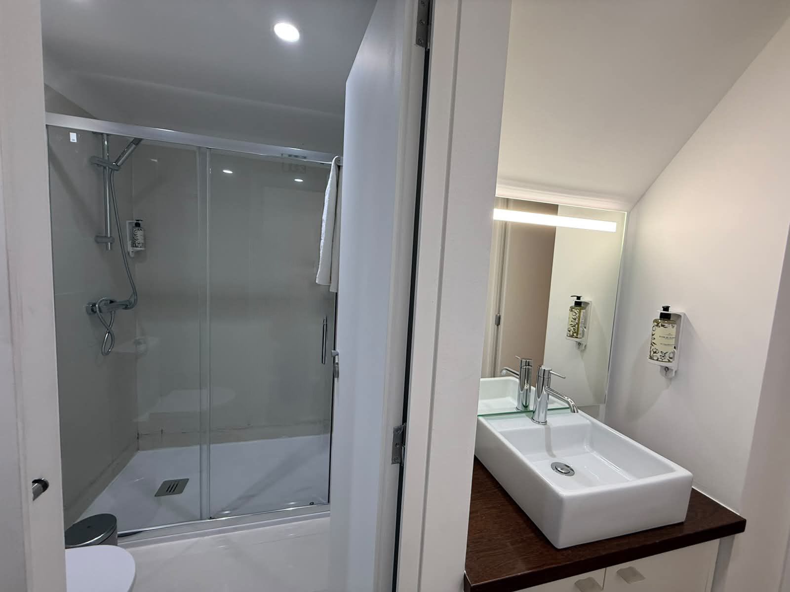 A modern bathroom with a glass-enclosed shower, a white sink, and a mirror above it.