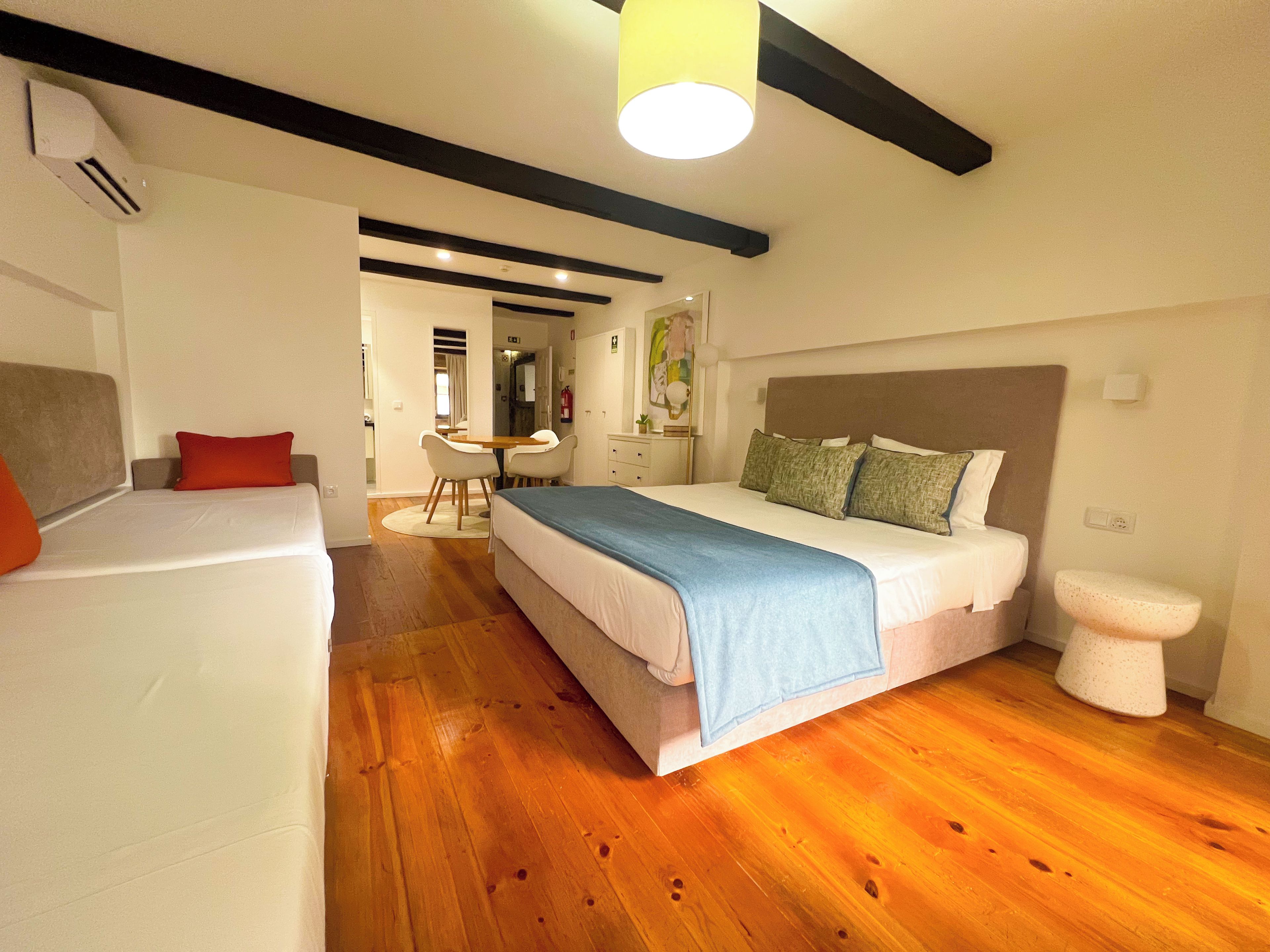 A bedroom with a bed, a sofa, a desk, and a toilet.