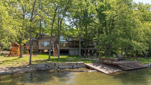 Un chalet au bord du lac, doté d’une terrasse, d’une balançoire et d’un quai s’avançant dans l’eau.