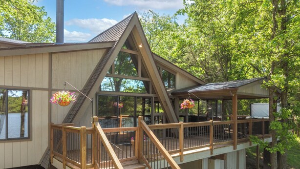 Une cabane dotée d’une terrasse en bois, d’un escalier et de jardinières suspendues.