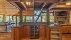 Une cuisine spacieuse dotée d’un grand îlot central, de poutres en bois, d’éléments décoratifs en pierre et d’une cheminée en pierre.
