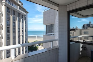 Un balcón con vista a la playa y al océano, una pared con azulejos y una barandilla.