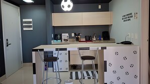 A compact kitchen with a central island, bar stools, and a wall-mounted soccer ball light. - SHB - Futebol e Praia Beira Mar (Santos)