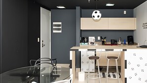 A modern kitchen with a central island, bar stools, and a glass dining table. - SHB - Futebol e Praia Beira Mar (Santos)