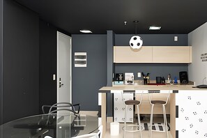 Een moderne keuken met een centraal eiland, barkrukken en een glazen eettafel.