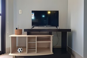 Een televisie op een zwart voetstuk, met een houten plank eronder.