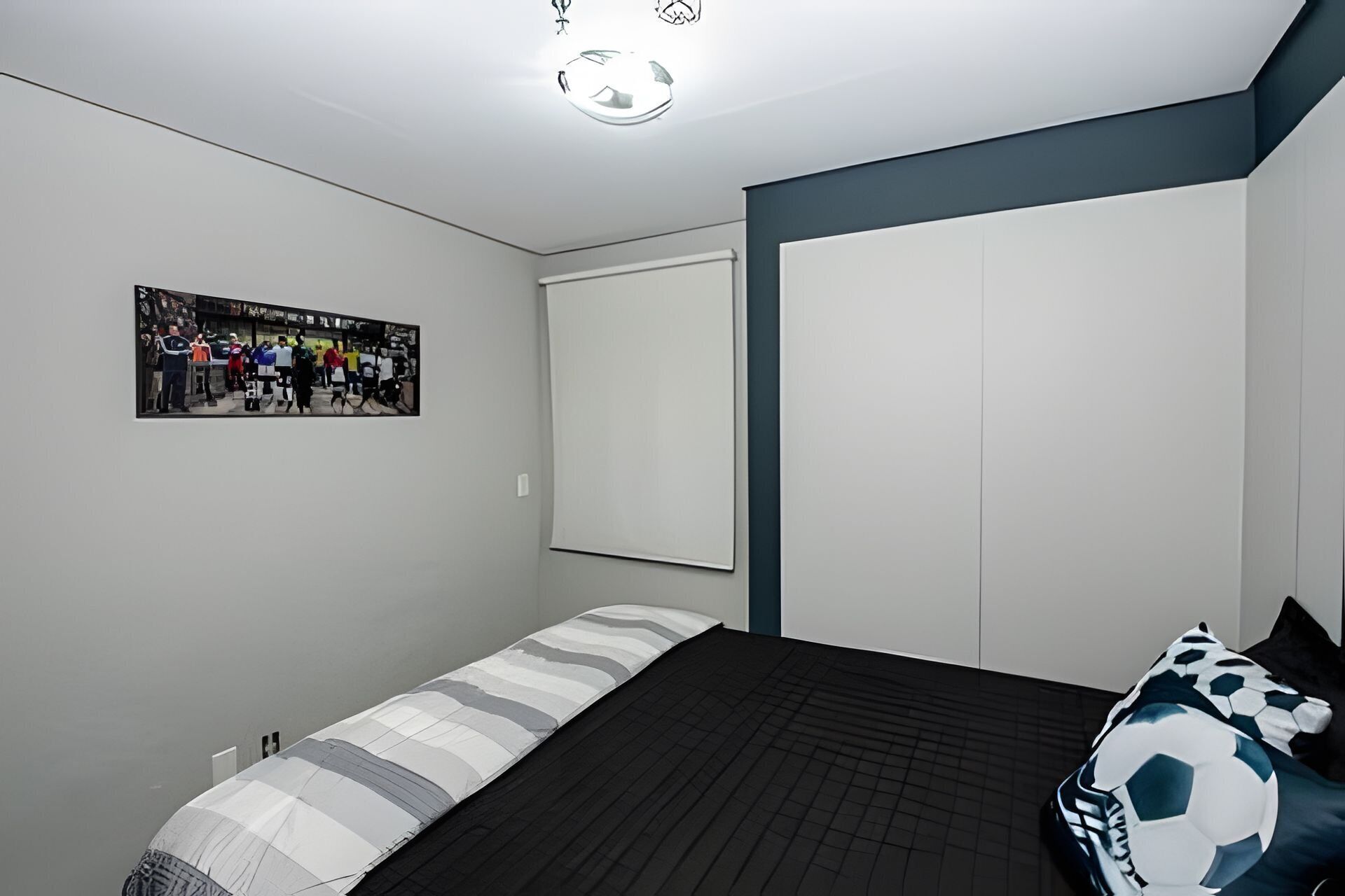 Um quarto com cama, guarda-roupa, um pôster na parede e uma luminária no teto.