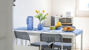 Ett matbord med stolar, en vas med gula blommor, en kanna och en tallrik med croissanter.