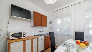 Keittiössä on mikroaaltouuni, liesi, kaappeja ja ruokailutila, jossa on pöytä kahdelle henkilölle.