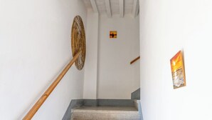 Een trap met een houten leuning, een decoratief object aan de muur, en een ingelijst schilderij.