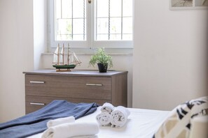 A bedroom with a bed, a dresser, a window with blinds, a potted plant, and rolled towels. - Lovely apartment in villa for 4 people with A/C, WIFI and TV (Porto Recanati)