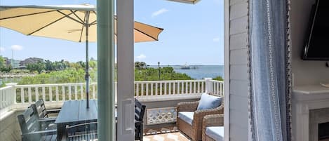 A covered outdoor seating area with a table and chairs, a view of the sea, and a fireplace.