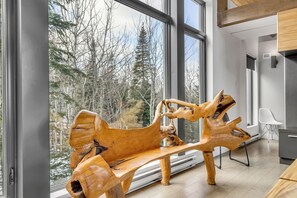 A modern interior with a large window, a wooden bench, and a minimalist design. - Le Refuge Montagnard (Petite-Rivière-Saint-François)