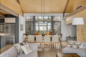 A modern kitchen with a refrigerator, dining table, and chairs. - Le Refuge Montagnard (Petite-Rivière-Saint-François)