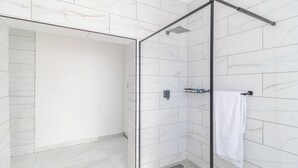 A modern bathroom with a glass shower enclosure, white marble tiles, and a towel rack. - Boutique Hotel-Style Room In Ferndale-C3 (Randburg)