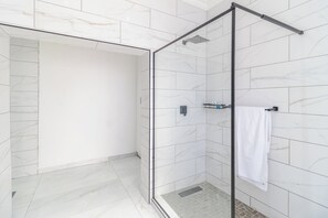 A modern bathroom with a glass shower enclosure, white marble tiles, and a towel rack. - Boutique Hotel-Style Room In Ferndale-C3 (Randburg)