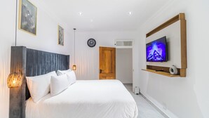 A bedroom with a bed, a TV, a clock, and a door. - Boutique Hotel-Style Room In Ferndale-C3 (Randburg)