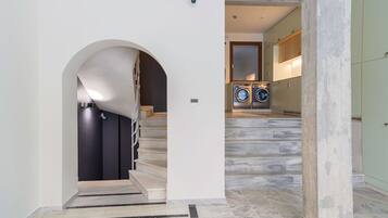 A modern interior with a staircase, a washing machine, and a large arched doorway.
