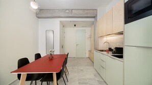 A modern kitchen with a microwave, a sink, and a dining area with a red table and black chairs. - Exarchia - Apartment for 4 pax (Athina)