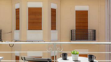 A balcony with a table, two chairs, a potted plant, and a railing.