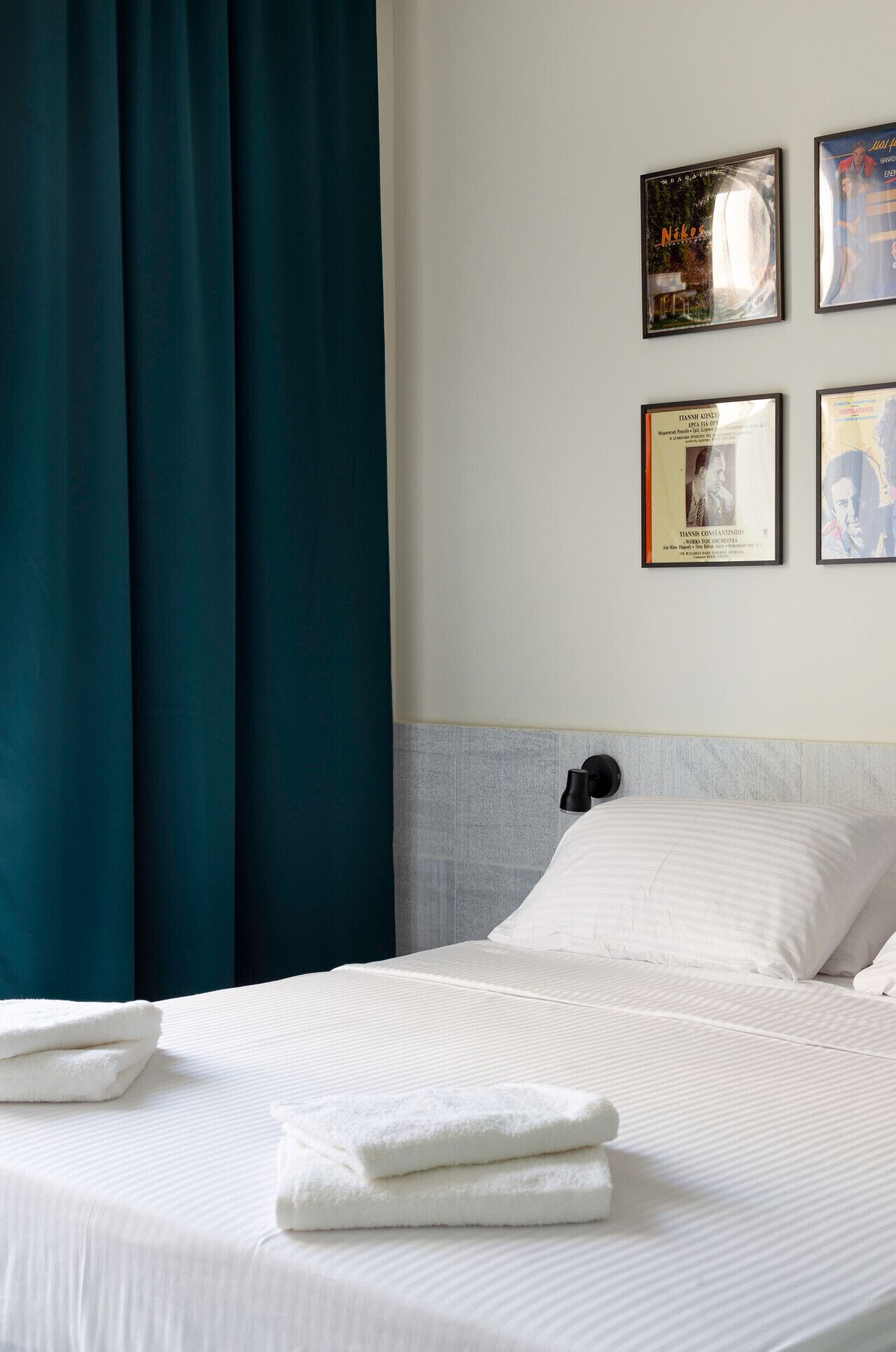 A hotel room with a bed, white linens, a headboard, and a wall with framed pictures.
