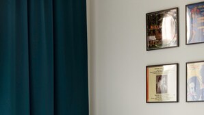 A hotel room with a bed, white linens, a headboard, and a wall with framed pictures. - Exarchia - Apartment for 4 pax (Athina)