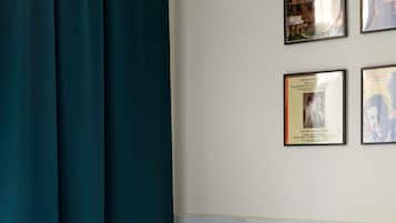 A hotel room with a bed, white linens, a headboard, and a wall with framed pictures.