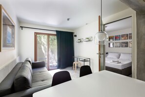 A modern room with a sofa, a dining table, a bed, and a small table with chairs. - Mooeve Exarchia - Roomy Apartment for 5 pax (Athina)