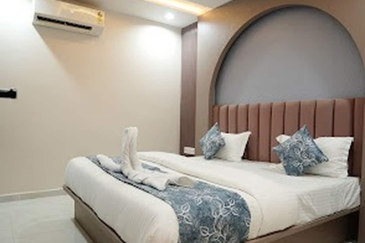 Une chambre à coucher avec un lit, des oreillers, une tête de lit et un appareil de climatisation.