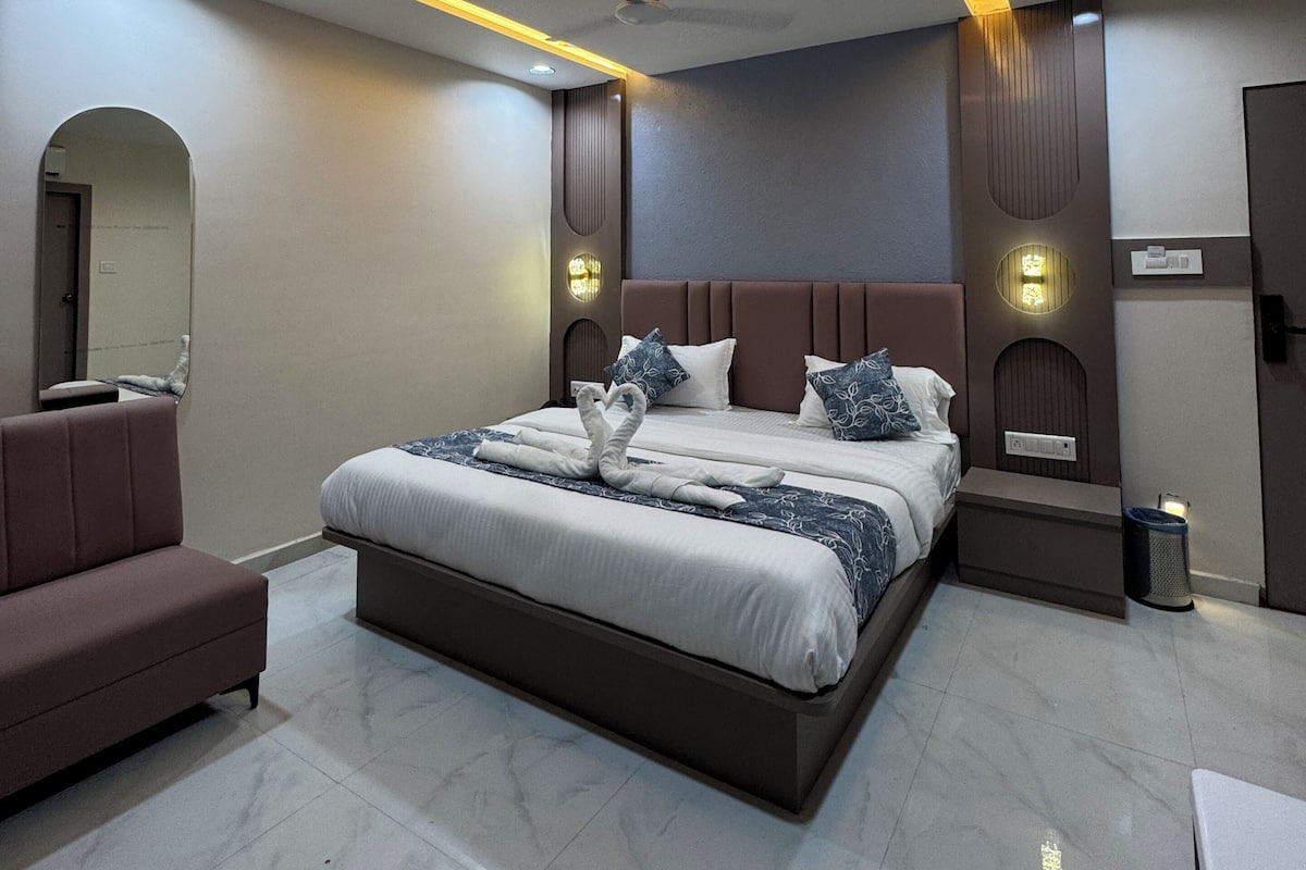 Une chambre d’hôtel moderne dotée d’un grand lit, d’un canapé, d’un ventilateur de plafond et d’un éclairage encastré.