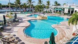 A swimming pool with a sun deck, lounge chairs, and palm trees. - Resort on Cocoa Beach: a 2 bedrooms Ocean View (Cocoa Beach)
