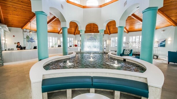 A spacious indoor pool with a central fountain, surrounded by seating and a reception area. - Resort on Cocoa Beach: a 2 bedrooms Ocean View (Cocoa Beach)