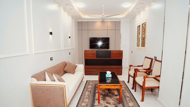 A modern living room with a sofa, chairs, a coffee table, a TV, and a patterned rug. - signature house luxor (Luxor)