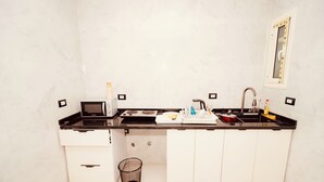 A kitchen with a black countertop, white cabinets, a sink, and a trash can. - signature house luxor (Luxor)