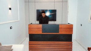 A modern reception desk with a flat-screen TV, a wooden finish, and a minimalist design. - signature house luxor (Luxor)