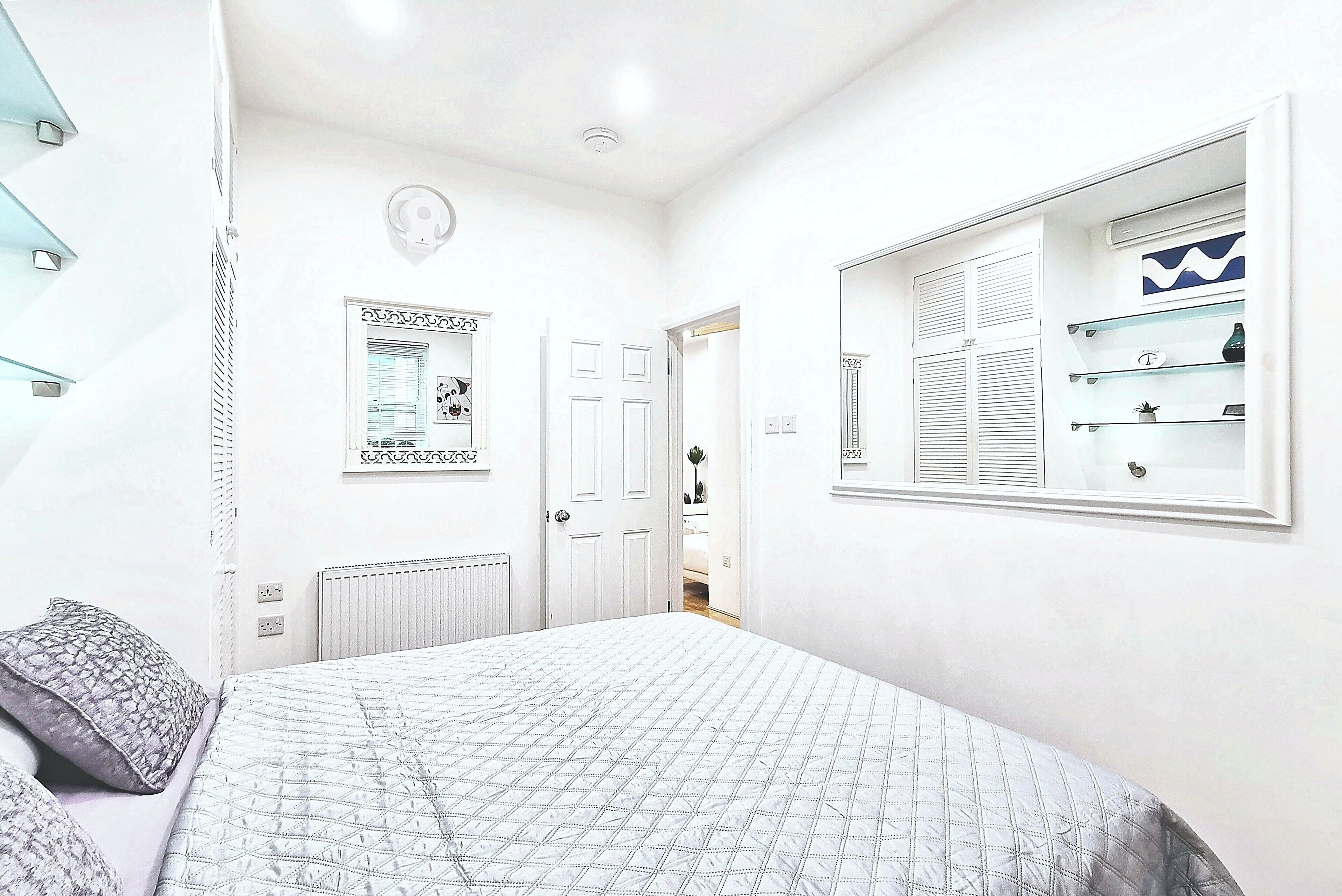 A bedroom with a bed, a dresser, a mirror, and a window with blinds.