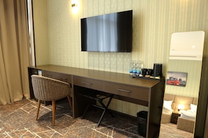 Une chambre d’hôtel équipée d’un téléviseur à écran plat fixé au mur, d’un bureau avec une chaise, d’une petite table avec une lampe et d’un tableau représentant Londres.