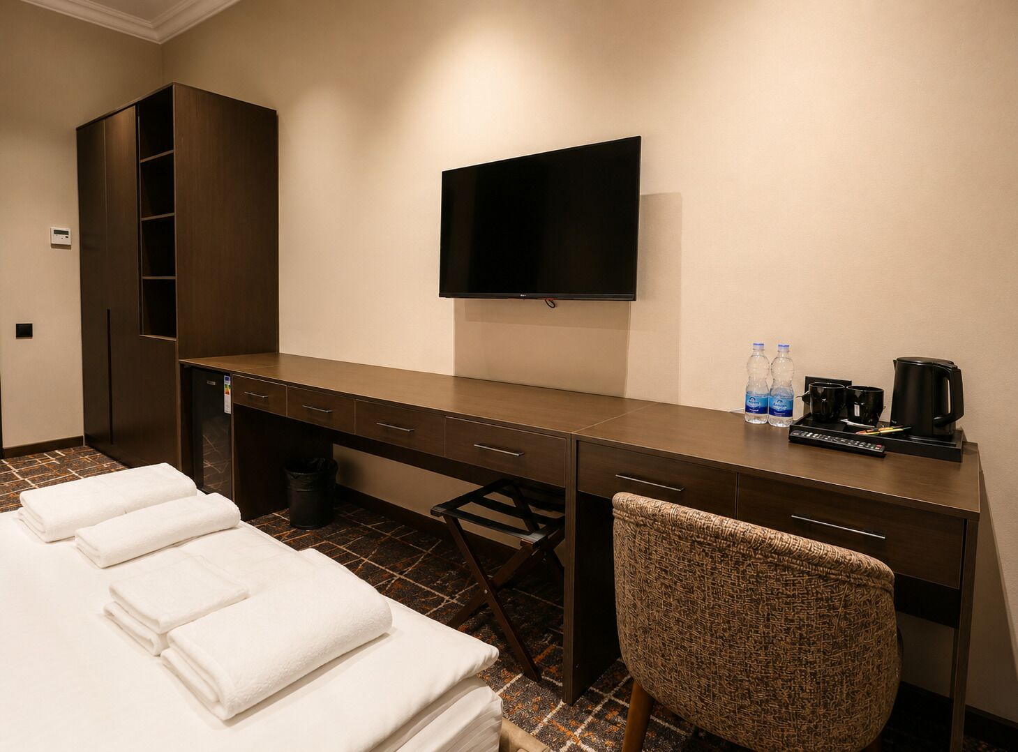 Une chambre d’hôtel avec un lit, un bureau, une télévision et une chaise.