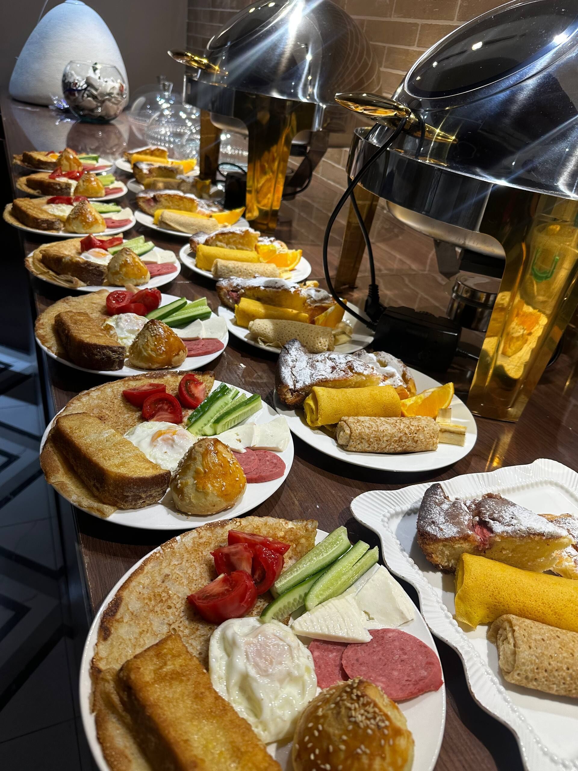 Un bufé con diversos alimentos, entre ellos tostadas, huevos y verduras.