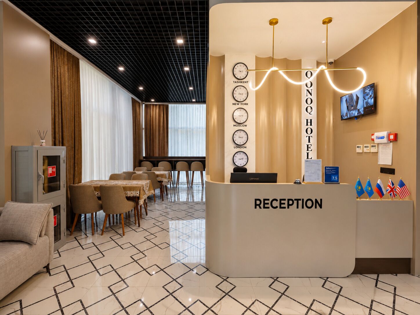 A hotel reception area with a reception desk, clocks displaying different cities, a television screen, and a flag display.