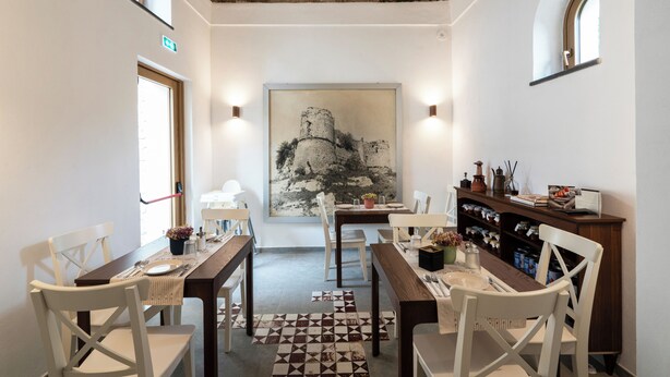 A dining area with a rustic ceiling, a large painting on the wall, and a bookshelf with books and decorative items. - N haidea - AgriFarm e B&B  (Lettere)