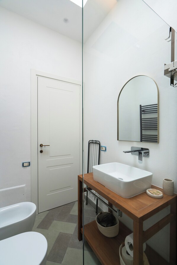 A modern bathroom with a white toilet, a white sink, a mirror, and a towel rack. - N haidea - AgriFarm e B&B  (Lettere)