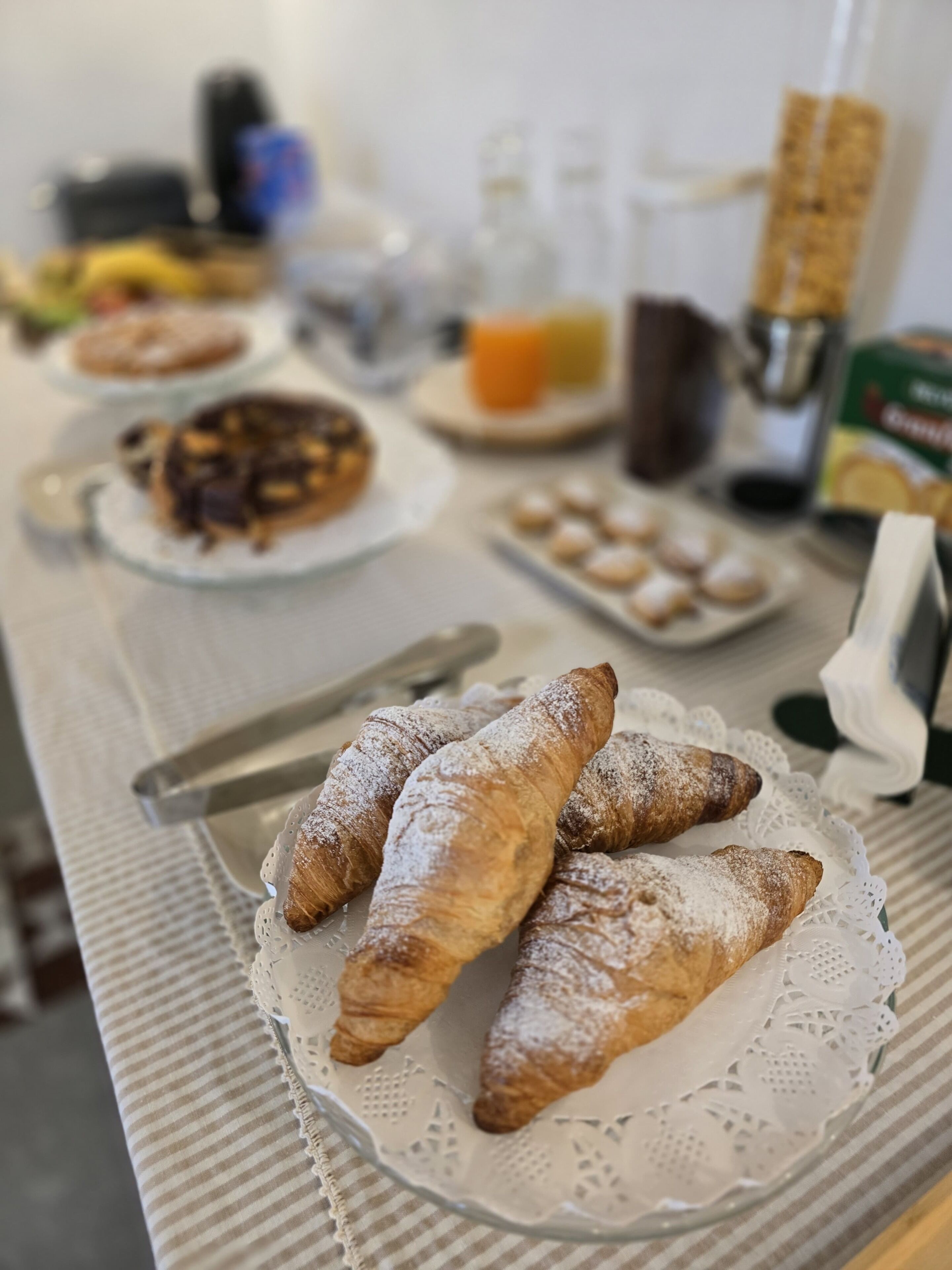 A breakfast table with pastries, a coffee pot, and a bottle of orange juice.