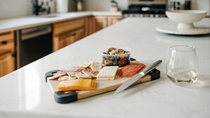A kitchen counter with a variety of cheeses, cured meats, and olives. - Alpine Ridge | Brand New Build | Sleeps 16 (Boyne City)