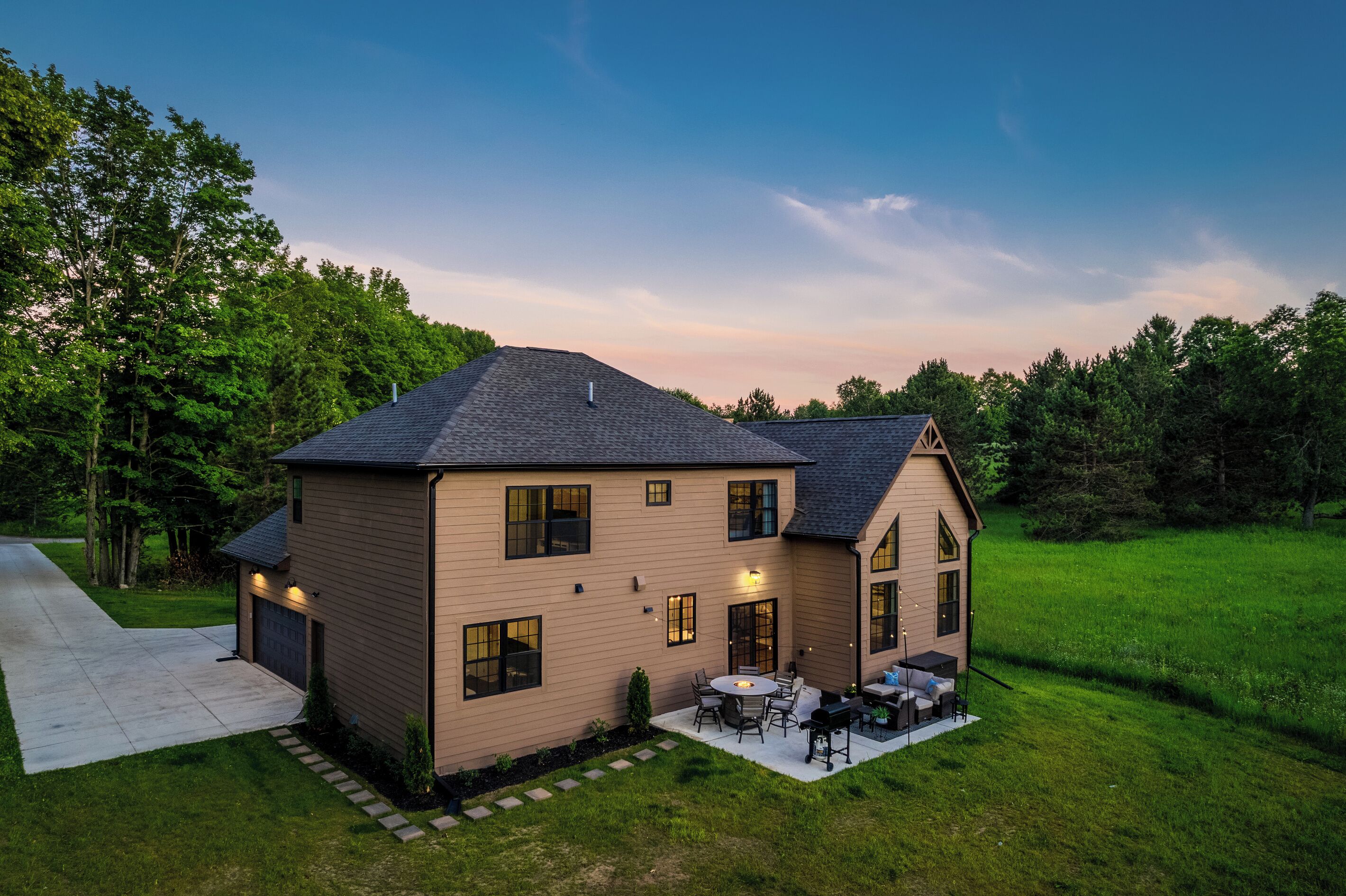 A two-story house with a covered patio, a driveway, and a well-maintained lawn.