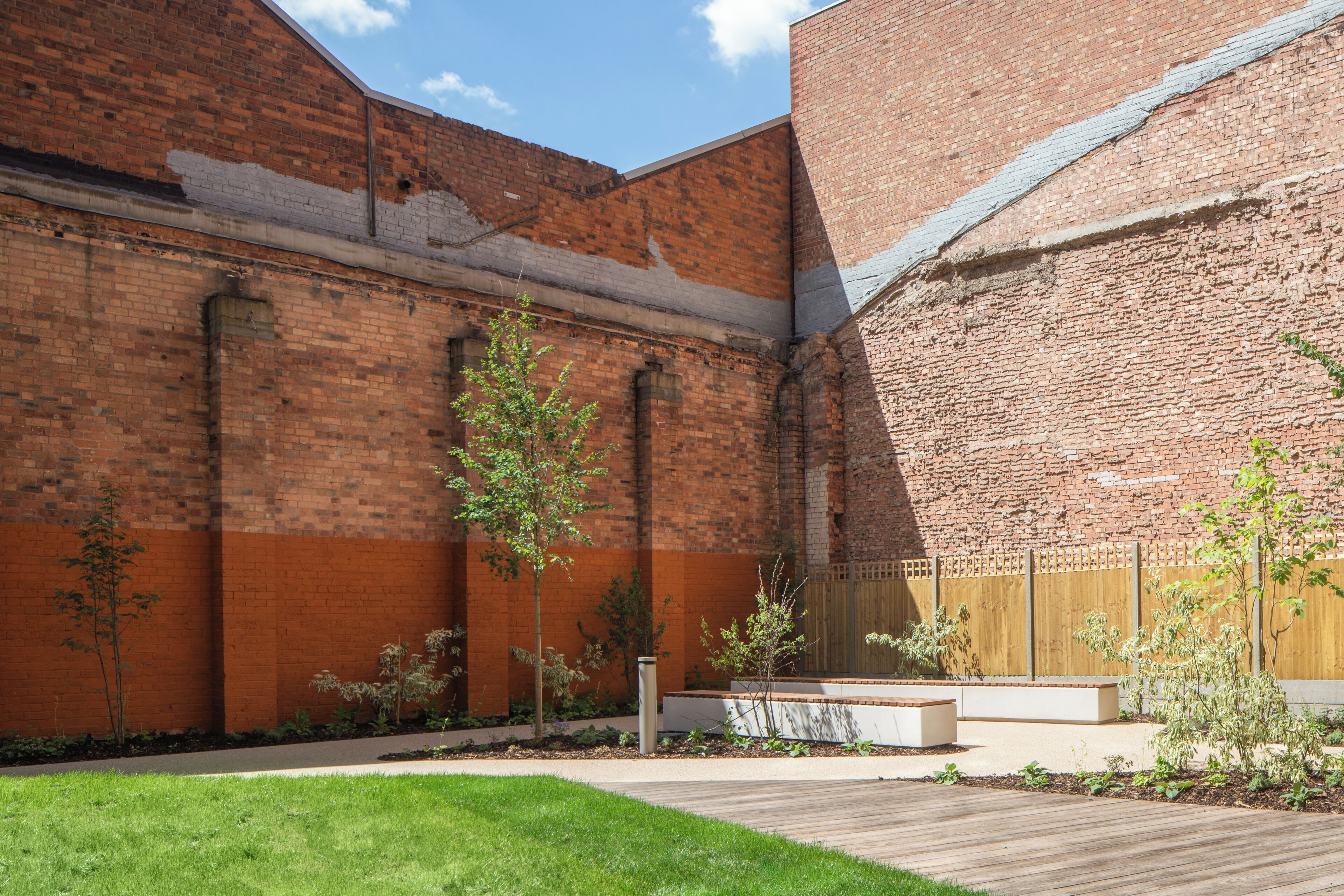 A courtyard with brick walls, a wooden deck, and small trees.
