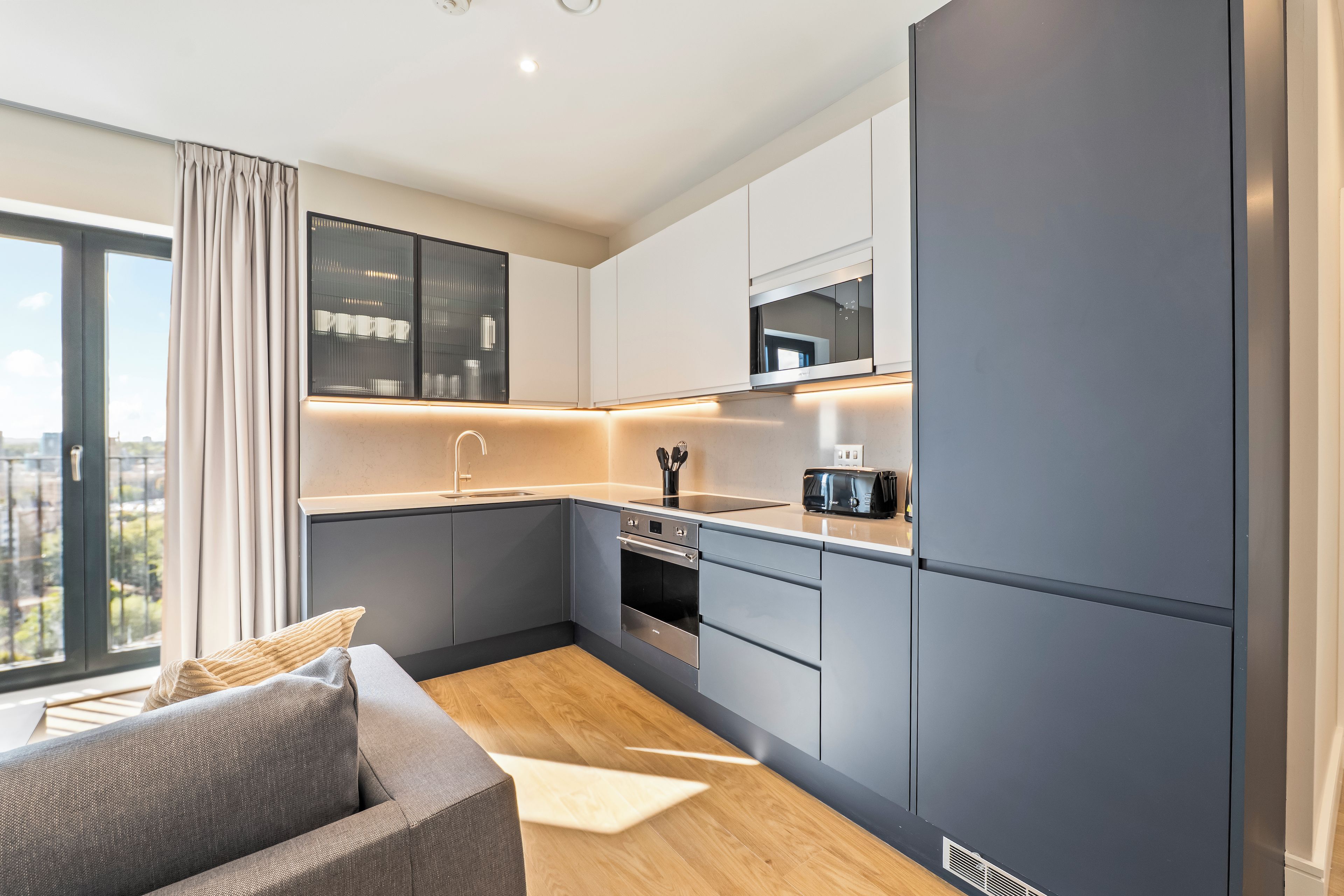 A modern kitchen with grey cabinets, a built-in oven, and a microwave.