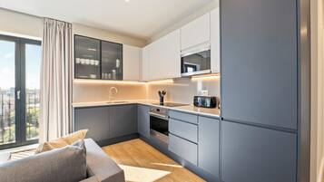 A modern kitchen with grey cabinets, a built-in oven, and a microwave.